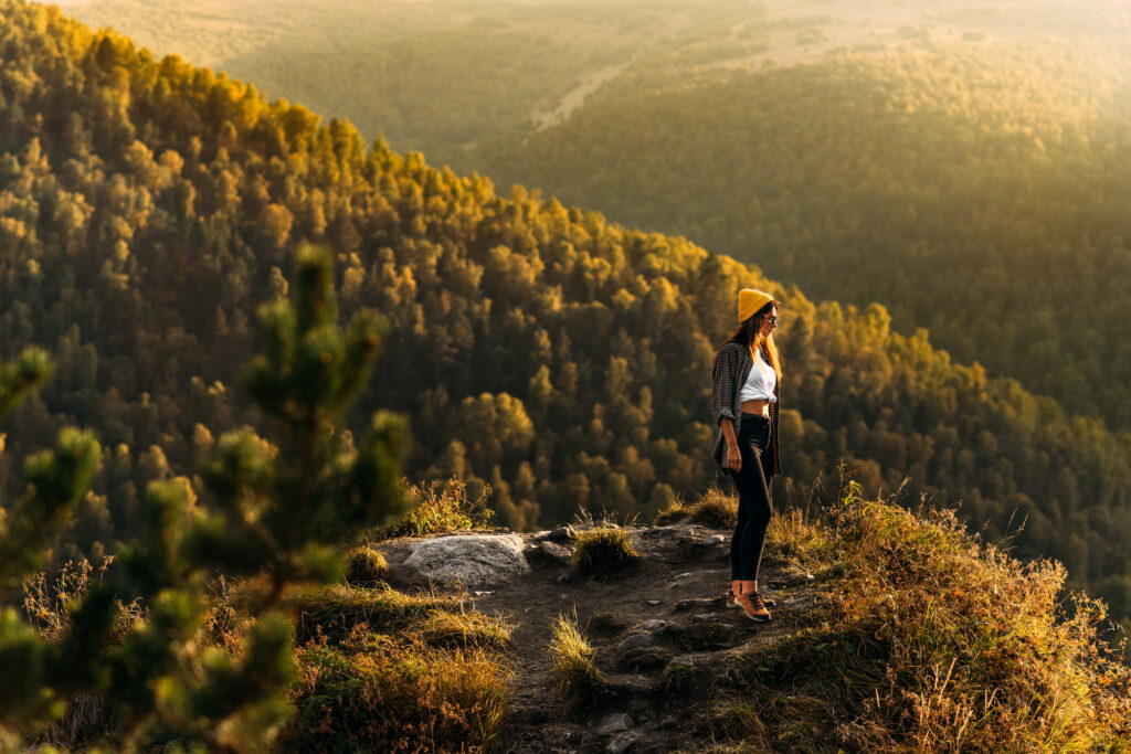 A woman meets the sunset in the mountains. Man travels in the mountains. Mountain tourism