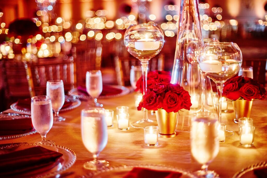 Luxury dining table setup with red roses on the glass vase decoration with candle light surrounded